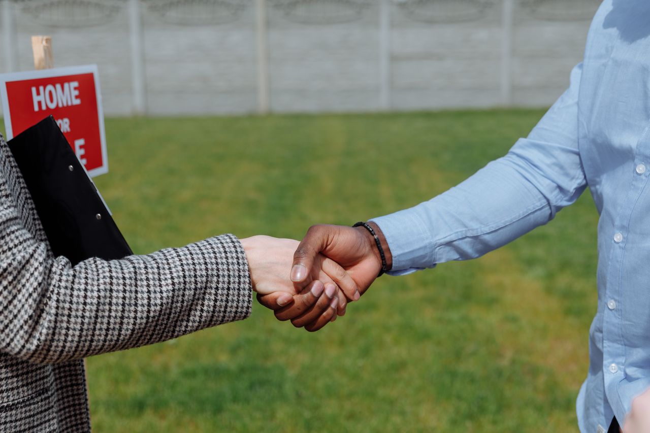 Close-up of a handshake symbolizing a real estate agreement outdoors.